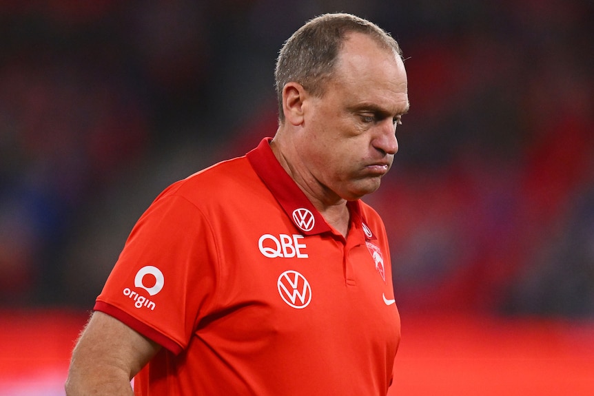 A man wearing Swans gear blows his cheeks out and looks downwards
