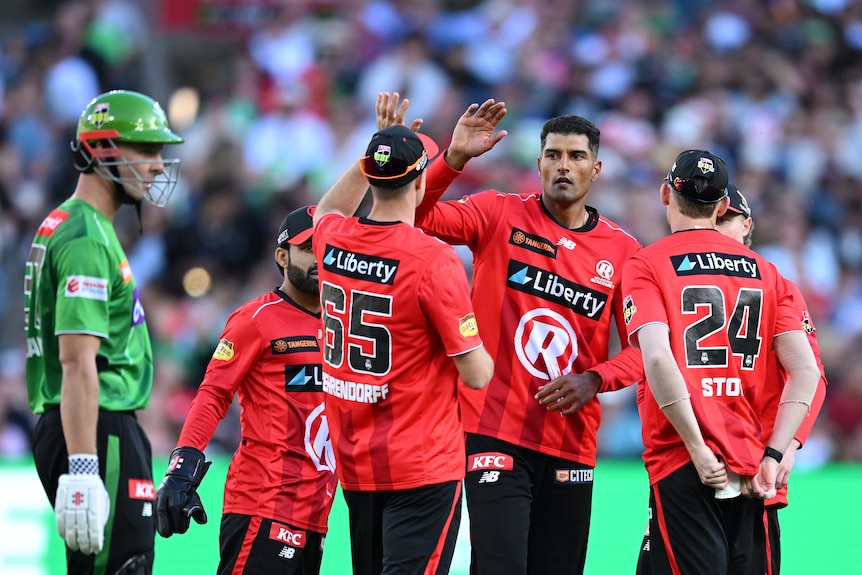 cricket plays dressed in red hi five on the pitch