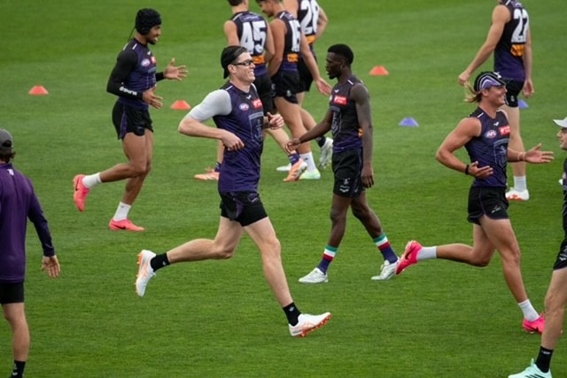 Dockers ruckman Mason Cox and other players jog through a drill during a training session.