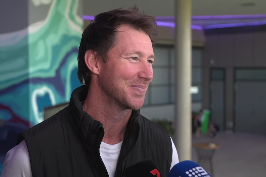 A man with brown hair smiles as he speaks to the ABC reporter