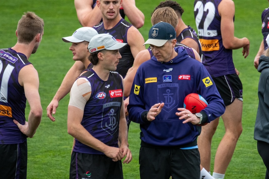 Dockers defender Jordan Clark talks to coach Justin Longmuir in front of other players during a training session.