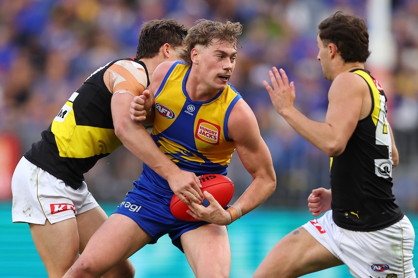Harley Reid fends off two Richmond players with the ball