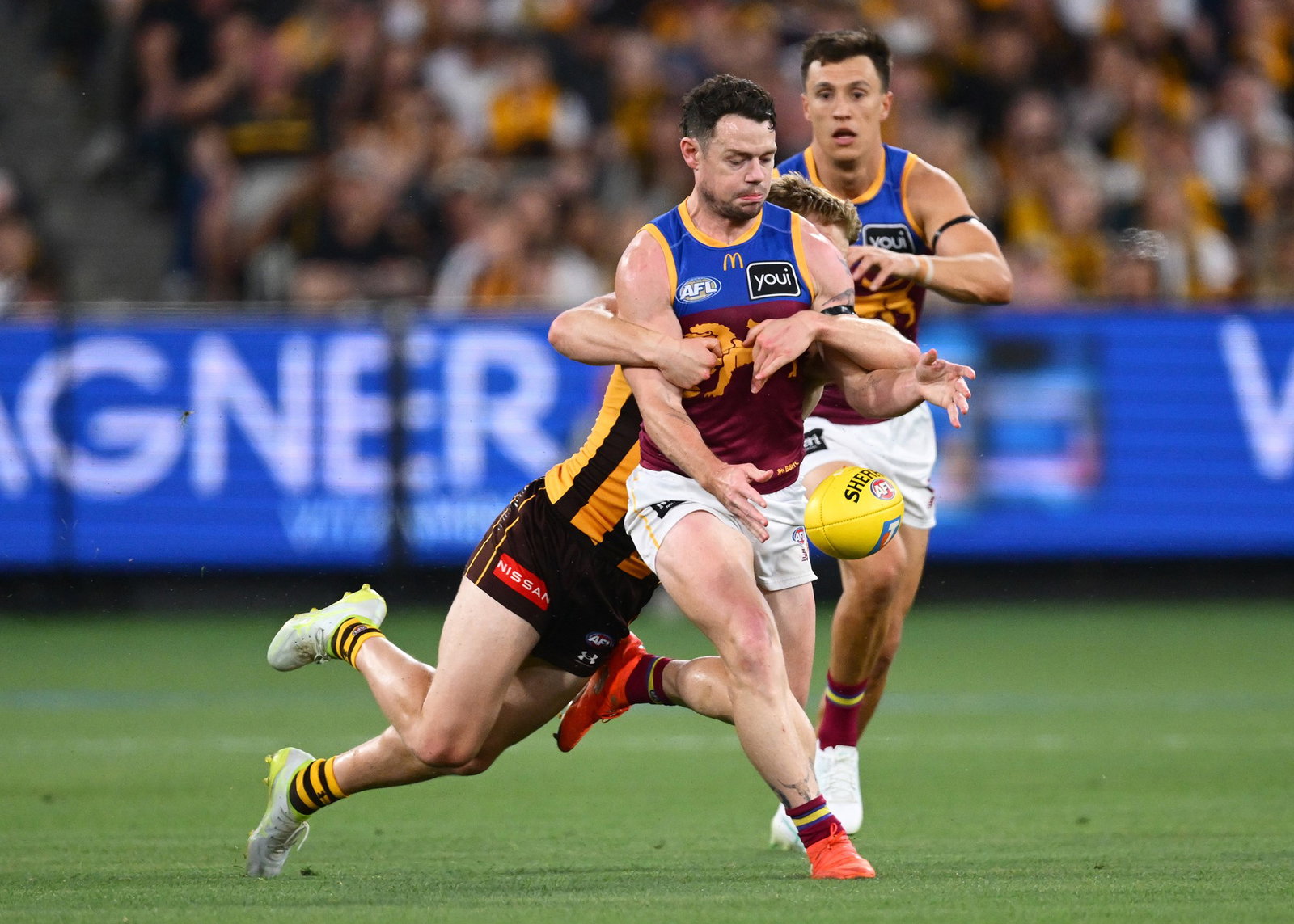 Lachie Neale of the Lions kicks whilst being tackled during the AFL Preliminary Final match between Hawthorn Hawks and Brisbane Lions at Melbourne Cricket Ground, on September 19, 2026, in Melbourne, Australia.