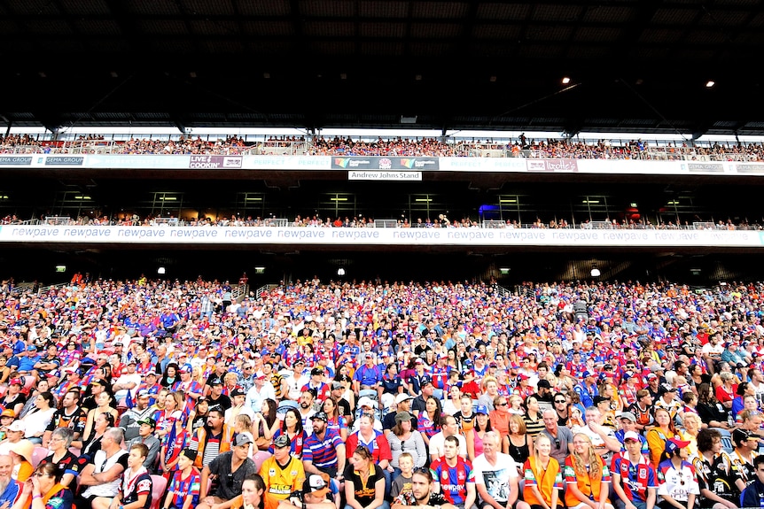 A group of fans watch a rugby league match 