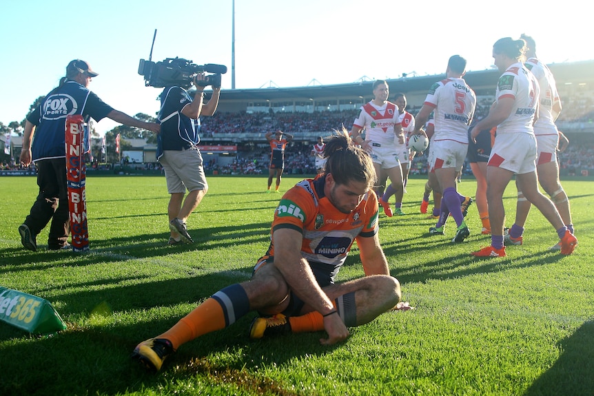 A man slumps to the ground after losing an NRL match 