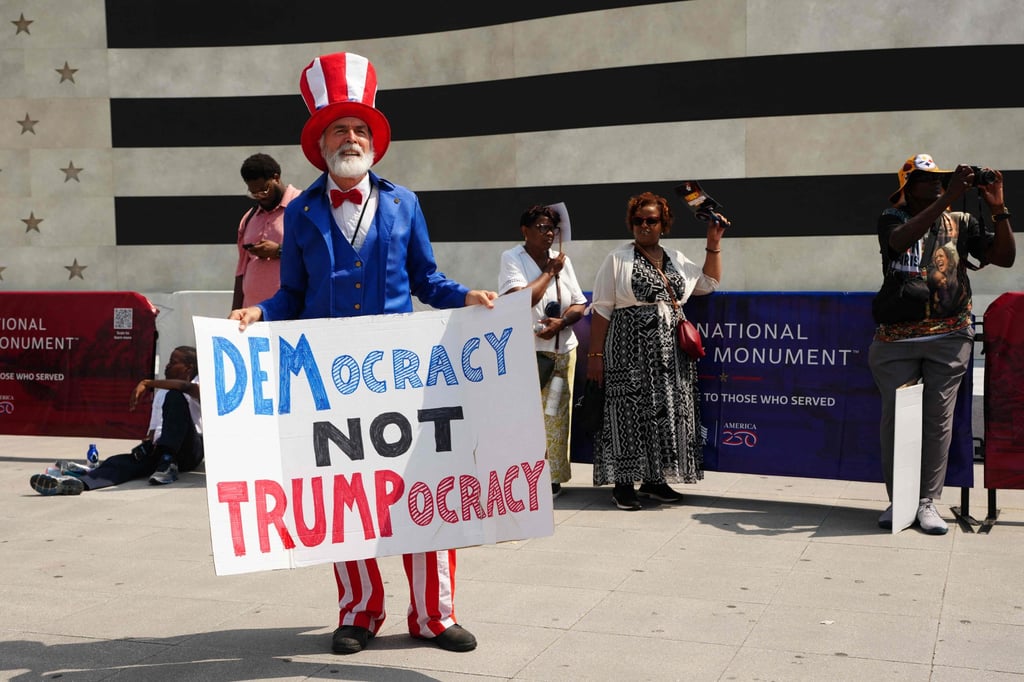 A man dressed in the colours of the US flag holds a sign reading “Democracy not Trumpocracy” during a “Defend the Vote” rally at the Lincoln Memorial in Washington in August. Photo: AFP