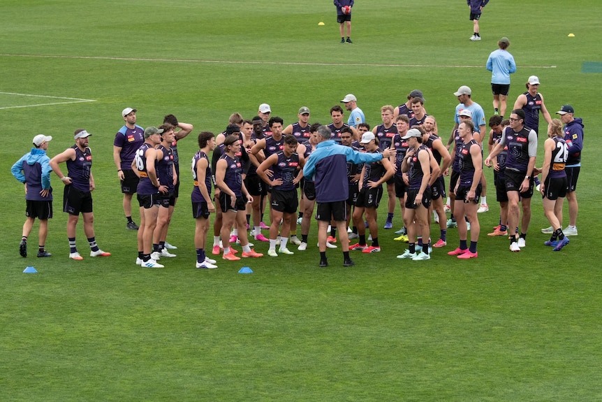 A wide shot of Justin Longmuir speaking to Dockers players on their training oval during an open training session.