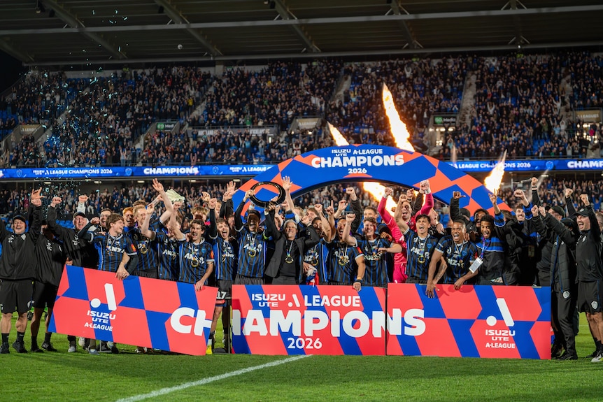 Auckland FC players celebrate with a banner saying 'A-League Champions 2026'.