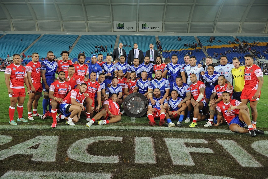 A group of players pose after a rugby league match/