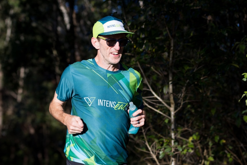 Man in green and yellow shirt, hat and sunglasses