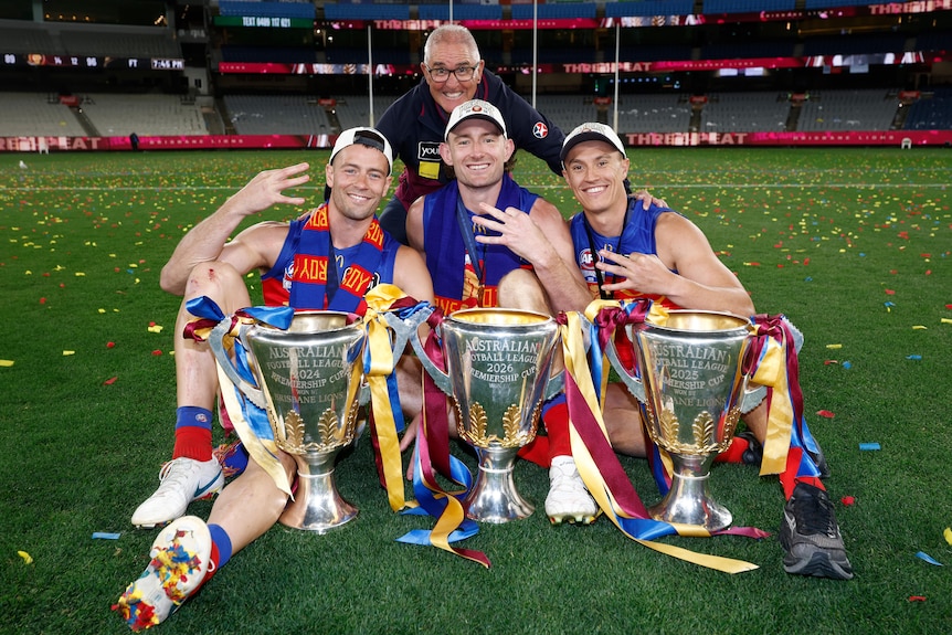 Josh Dunkley, Chris Fagan, Harris Andrews and Hugh McCluggage pose with three afl trophies