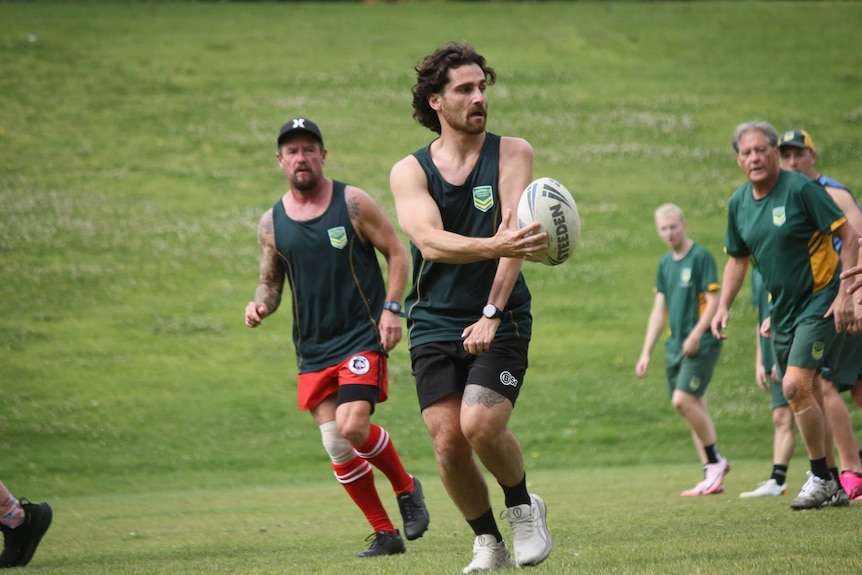 A male physical disability rugby league player passes the ball with his right hand