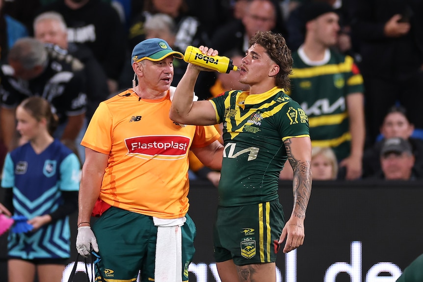 Kangaroos fullback Reece Walsh having a drink with a trainer next to him