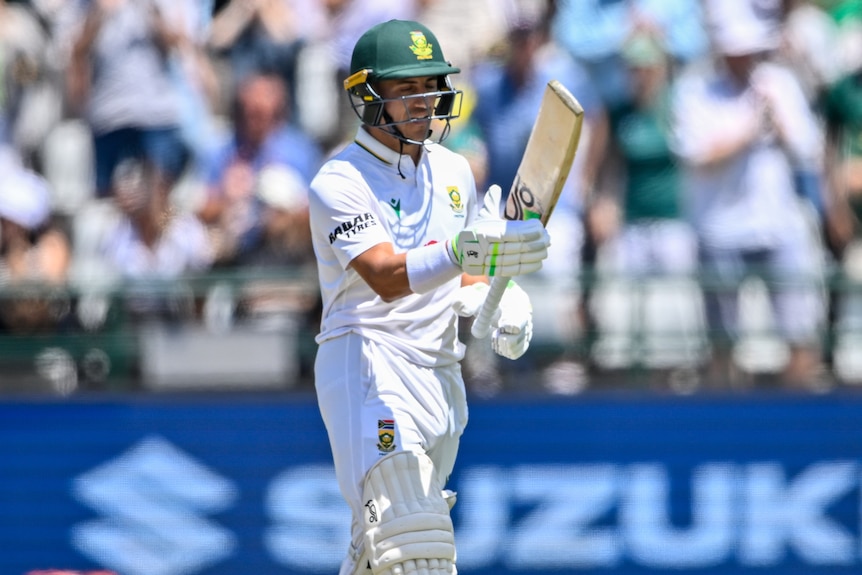 A cricket batter raises his bat after passing 50